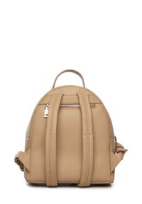 Mochila de cuero beige con forma redondeada, dos correas para el hombro y una asa en la parte superior. Cuenta con un bolsillo con cremallera en la parte trasera y un acabado texturizado.