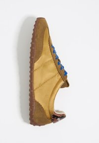 Scarpa di tessuto marrone con lacci blu, caratterizzata da una tomaia testurizzata, una punta rotonda e una suola in gomma marrone con accenti decorativi sul tallone.