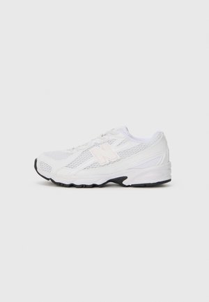Hvid mesh- og læder-sports sneaker med sort sål og lyserøjt "N"-logo på siden, vist i højre profil på grå baggrund.