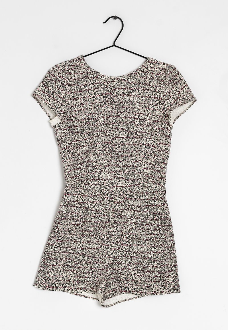 Combinaison femme à manches courtes avec motif tweed multicolore, suspendue sur un cintre noir sur fond blanc.