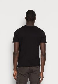 Tricou negru cu mânecă scurtă din bumbac, design cu guler rotund, textură netedă, croială ajustată. Purtați cu șorturi cargo întunecate, văzut din spate.