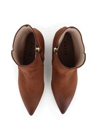 Bottines en daim marron avec un orteil pointu, un col incurvé et des accents de fermeture éclair dorés. L'intérieur est lisse et de couleur claire.