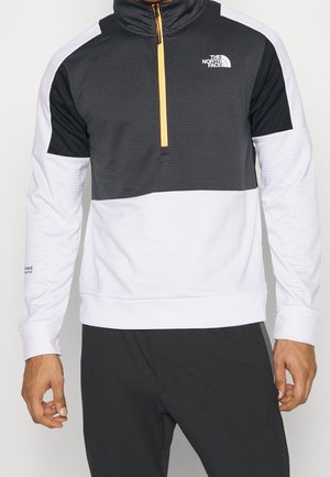 Pullover a zip con quarti in bianco e nero con zip arancione. Presenta una parte superiore nera testurizzata e una parte inferiore bianca liscia.