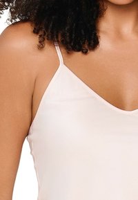 Lys pink camisole med tynde stropper, V-hals design og glat, satinlignende tekstur. Har minimalistiske syninger i kanterne.