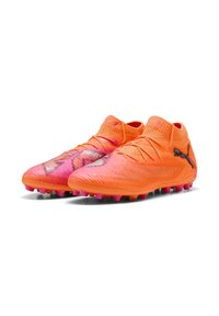 Scarpe da calcio arancione brillante con tomaia testurizzata, dettagli rosa e collo a calzino. Presentano tacchetti conici sulla suola per una migliore aderenza.