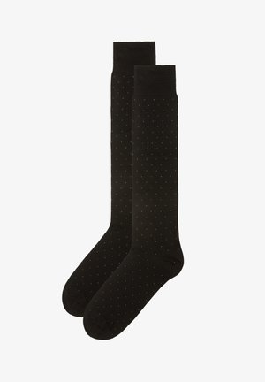 Medias negras hasta la rodilla con una textura suave, que presentan un patrón de pequeños lunares blancos distribuidos uniformemente por toda la superficie.