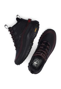 Bottes imperméables noires avec accents rouges, dessus texturé, semelle robuste avec crampons profonds, lacets à motif et talon renforcé. Semelle extérieure Vibram.