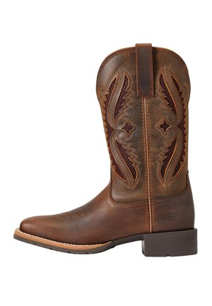 Brun cowboystøvle i læder med dekorative syninger og trækflap, med lav stablet hæl og afrundet firkantet snude.