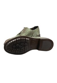Scarpa oxford in camoscio verde con dettagli brogue, suola in pelle e battistrada in gomma testurizzata, con accenti marroni sulla suola e ai bordi.