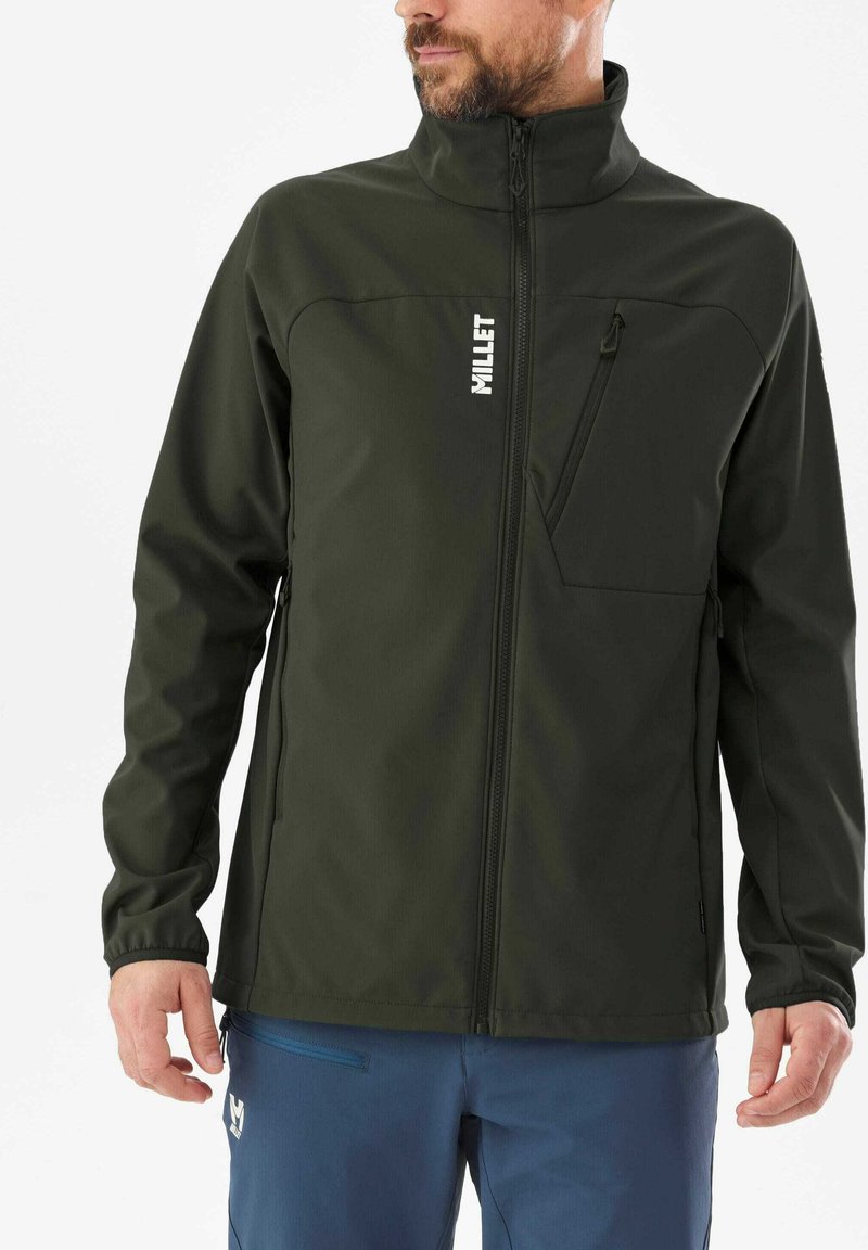 Veste softshell vert foncé avec un col haut, fermeture éclair frontale et poches latérales. Présente un logo sur la poitrine gauche et une poche zippée.