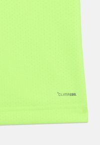 Neon zöld sportszövet, hálós textúrával, kis perforációkkal. Az alsó jobb sarokban "CLIMACOOL" címke található.