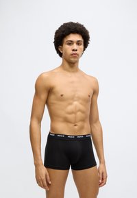 Boxers pretos de algodão com cintura elástica com a marca. O design é ajustado e suave, com comprimento curto nas pernas e laterais sem costuras.