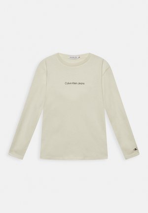 Långärmad, krämfärgad t-shirt i bomull. Har en svart "Calvin Klein Jeans"-logotyp på bröstet och en liten logotyp på ärmen.