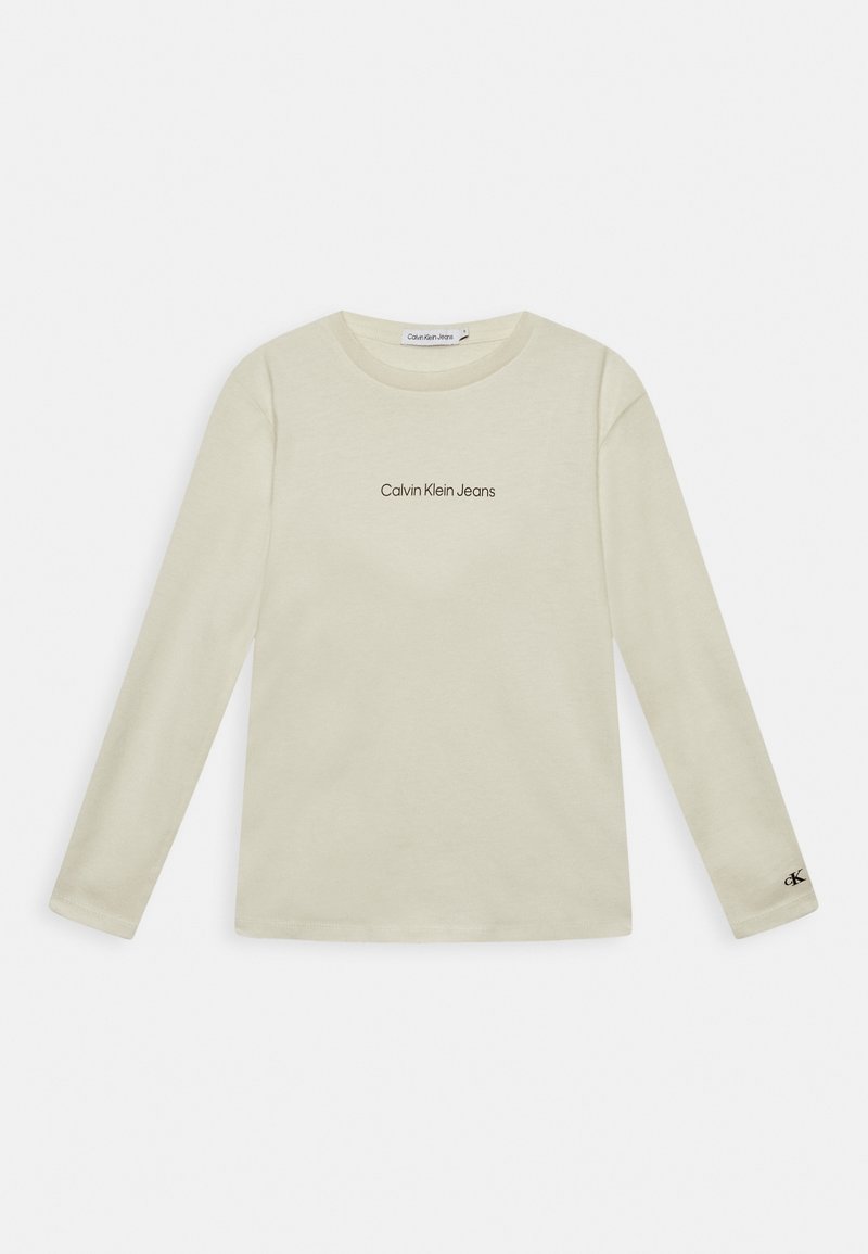 Dlouhá rukáv, krémové tričko vyrobené z bavlny. Obsahuje černé logo "Calvin Klein Jeans" na hrudi a malé logo na rukávu.