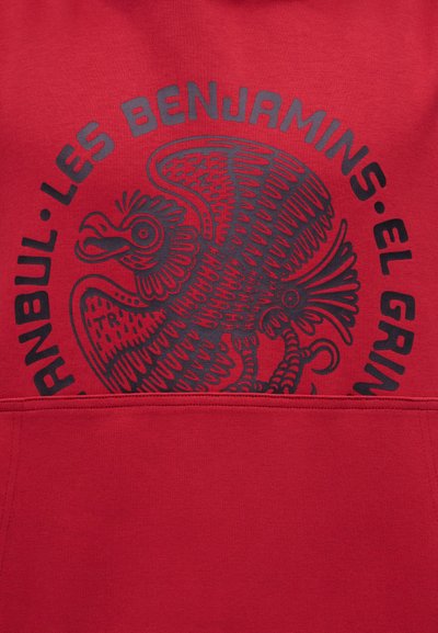 Rode stof met een zwart grafisch ontwerp van een gestileerde vogel en tekst met de woorden "ANNBUL LES BENJAMINS EL GRING".