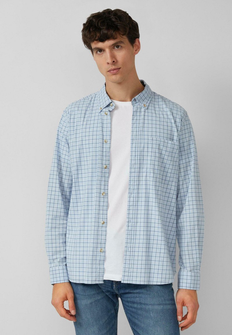 Lichtblauw geruit shirt met button-down kraag, lange mouwen, witte knopen, enkele borstzak, gedragen over een wit T-shirt.