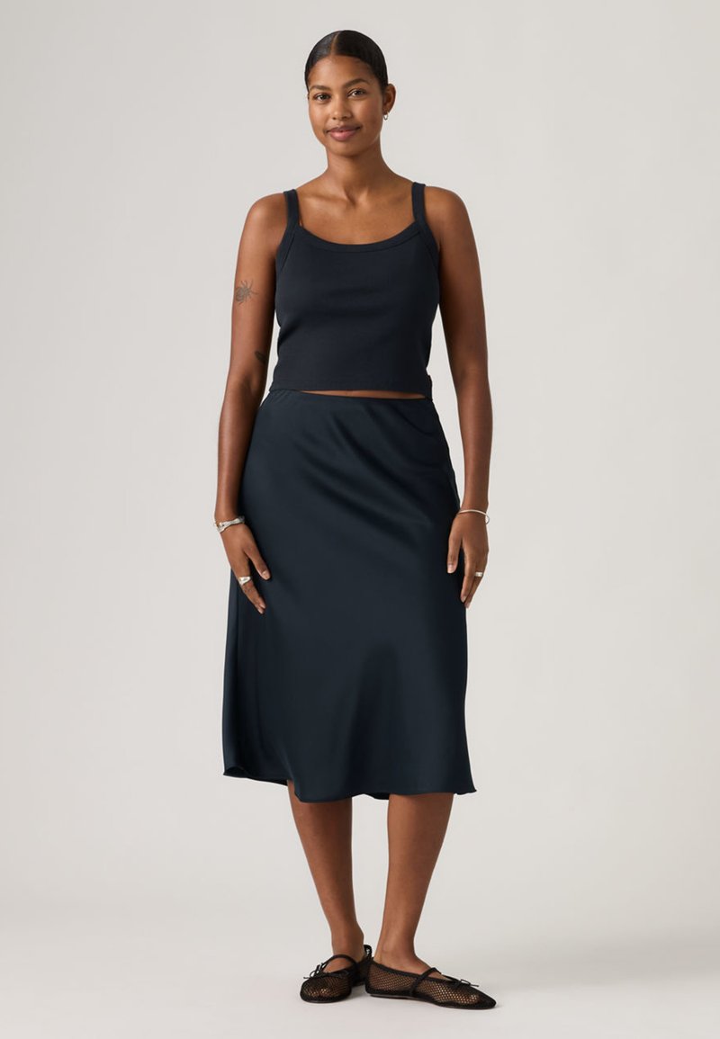Navy blue cropped tank top and matching midi skirt with a smooth texture. The outfit is complemented by black mesh flats.