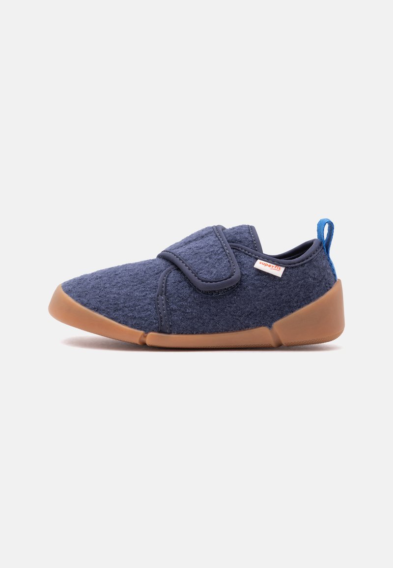 Chaussure en tissu doux bleu marine avec semelle en caoutchouc marron, bride velcro et languette bleue au talon.