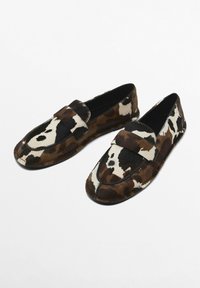 Brown and white patterned loafers made from soft fur, featuring a rounded toe and a front strap across the upper. Smooth black interior.