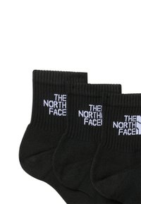 Sorte svarte bomull ankelsokker med ribbede mansjetter og "THE NORTH FACE"-logo i hvitt. Solgt i pakker med tre par.