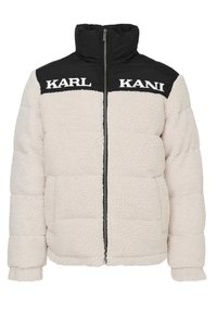Giacca puffer in pile color crema con parte superiore in nylon nero. Presenta un colletto alto, chiusura con zip e ampi tasconi frontali. Marchio visibile sulle spalle.