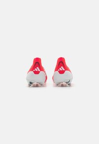 Red synthetic soccer cleats with a textured upper, white accents, and transparent studs, featuring a snug, streamlined shape.