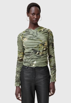 Camicia a manica lunga verde oliva con stampa floreale, caratterizzata da lati arricciati per aggiungere texture. Abbinata a pantaloni in pelle nera.