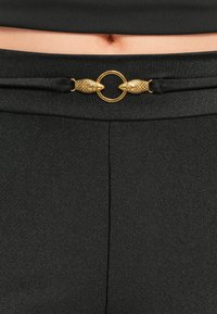 Black pants with a smooth texture, featuring a gold snake-shaped buckle at the waist, adding a distinct accent.