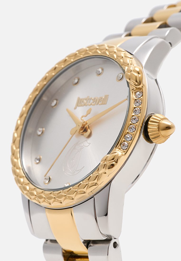 Montre en argent et doré avec une lunette tressée dorée, cadran argenté avec des marqueurs d'heure en cristal, et un bracelet poli avec des accents de couleur.