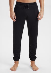 Sorte sweatpants med elastiske manchetter og snor i taljen, lavet af blødt stof, designet til komfort og en afslappet pasform.
