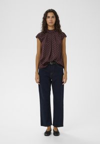 Tmavobordová blúzka s imitáciou stojatého goliera a bezrukávovým dizajnom, zdobená bielymi bodkami. Kombinovaná s tmavomodrými džínsami s vysokým pásom a širokými nohavicami.