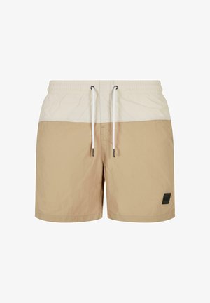 Beige Badehose mit einem hellbeigen oberen Bereich. Sie verfügt über einen elastischen Bund mit Kordelzug und einem kleinen schwarzen Logo-Patch.