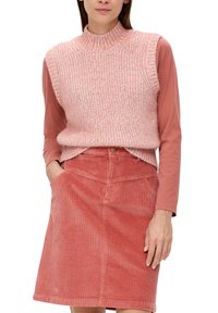 Strick-Pink ärmelloses Oberteil über einem langärmligen pinken Top, kombiniert mit einem gerippten Cordrock in Pink, der über Taschen und einen Knopf vorne verfügt.