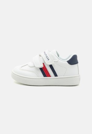 White sneakers with two horizontal stripes, one red and one navy, and Velcro straps. Made from smooth synthetic material with a rubber sole.