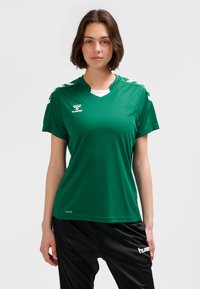 Green short-sleeve soccer jersey with a V-neck, white accents on the shoulders, and logo on the chest. Smooth, moisture-wicking fabric.