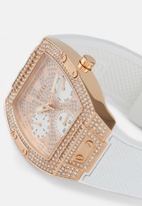 Montre en or rose avec un boîtier carré, accents en cristal, bracelet texturé blanc et double sous-cadran pour l'affichage de la date et du jour.