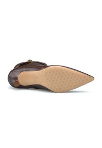 Scarpa alta in pelle marrone con punta appuntita, superficie liscia, dettagli dorati e suola in gomma testurizzata con una battistrada decorata.