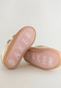 Kaksi kultaisia lasten lenkkareita, joissa on vaaleanpunaiset kumipohjat ja valkoisella taustalla "SNEAKER"-teksti.