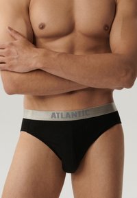Czarne majtki z srebrnym paskiem z napisem "ATLANTIC" w kolorze szarym. Gładka tekstura, dopasowany krój.