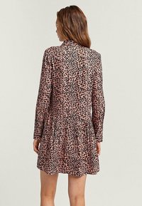 Vestido de leopardo en rosa y negro, con mangas largas, falda plisada y cuerpo ajustado. Tejido suave con una textura lisa.