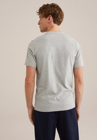 Camiseta de algodón gris con cuello redondo y mangas cortas, de corte relajado, textura suave, costuras visibles y un diseño liso en la parte posterior.