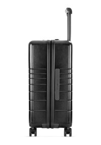 Black hard-shell suitcase with a textured finish, vertical grooves, retractable handle, and four wheels for mobility. Brand label visible.
