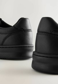 Zwarte leren sneakers met een gladde textuur, ronde vorm en gestikte details. Voorzien van een zachte zwarte rubberen zool.