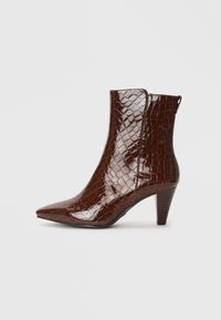 Bocanci până la gleznă din piele lacuită maro, cu textură de crocodil, vârful ascuțit și toc de 3 inch. Au un design fără cusături și fermoar în partea din spate.