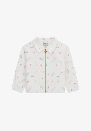 Giacca bianca con zip e colletto, decorata con piccoli cuori rosa e parole stampate come "GUESS", "LOVE", "GIRL" e "1981".