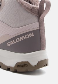 Salomon jalatsid, millel on hall ja purpurpunane ülalosa, pehme tekstuuriga krae, Contagrip tald ning silmapaistev bränding küljel.