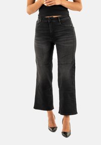 Jeans in denim nero a gamba larga con vita media, tasche frontali e sbiaditure sottili. Il tessuto ha una texture liscia e uno stile classico.