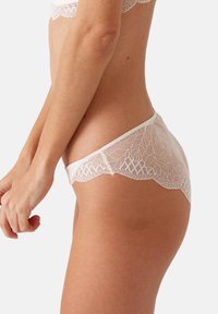 Lace hipster ondergoed in een lichte romige beige, met een bloemenpatroon, golvende randen en een gladde, zachte textuur.