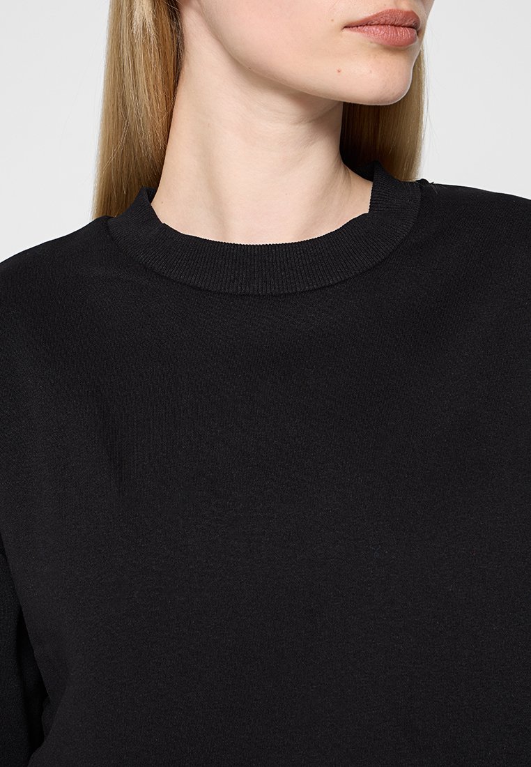 Zwarte sweatshirt met een ronde hals, gemaakt van zacht materiaal. Heeft een ribbelstructuur bij de hals. Geen zichtbare patronen of accenten.