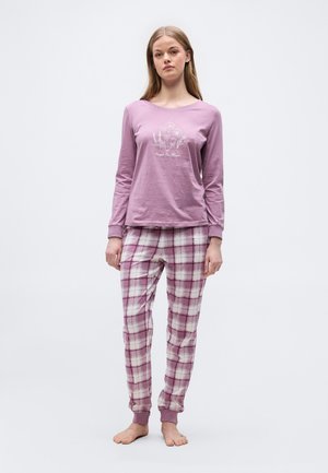 Junge Frau steht barfuß und trägt ein mauvefarbenes langärmliges Oberteil mit Blumenmuster und mauve-weiß karierte Schlafanzughose.